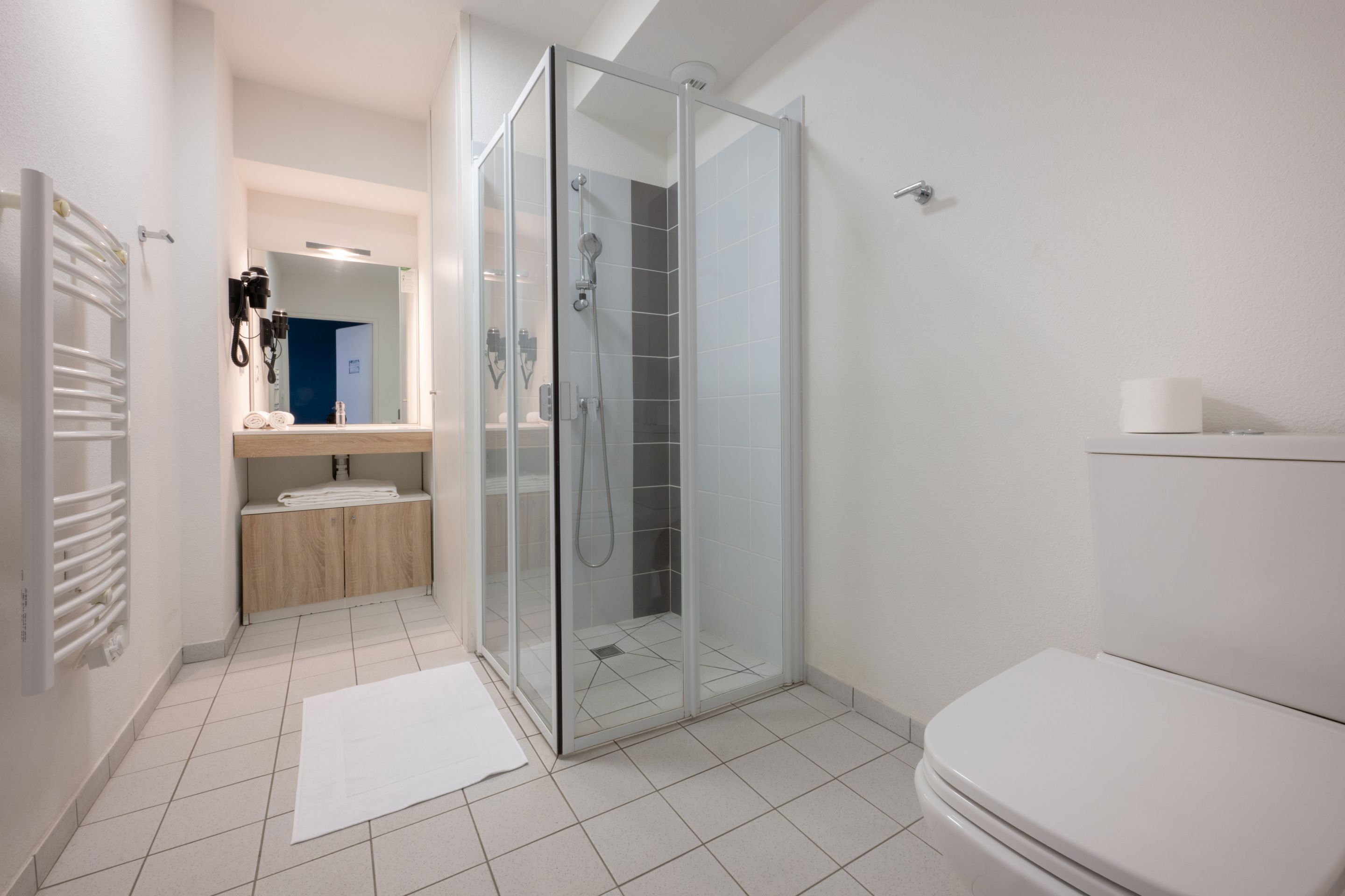 Ein modernes Badezimmer mit einer Duschkabine, einer Toilette und einem Waschbecken mit Spiegel.