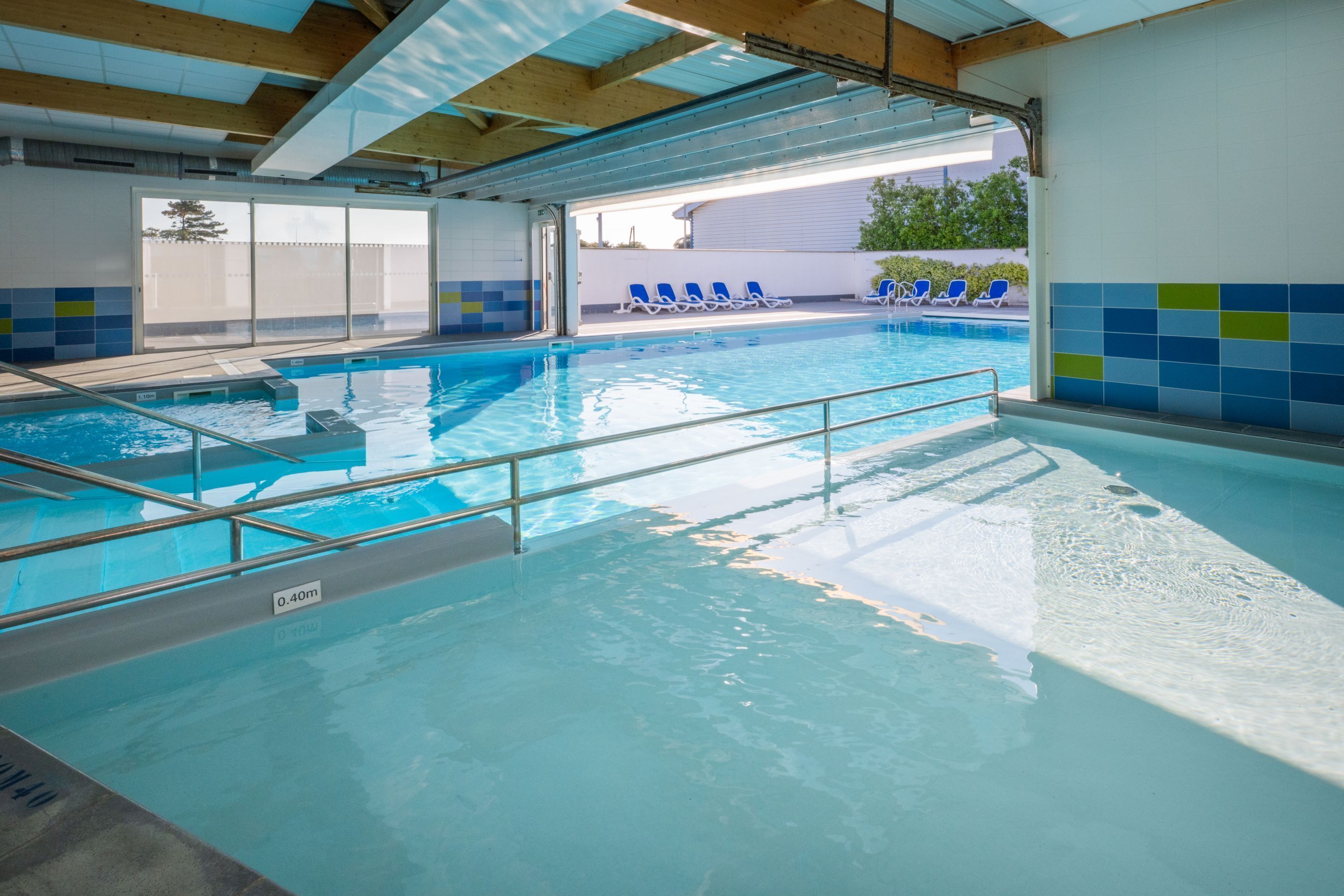 Une piscine intérieure à l’eau claire, dotée d’un plongeoir et d’un toit ouvrant.
