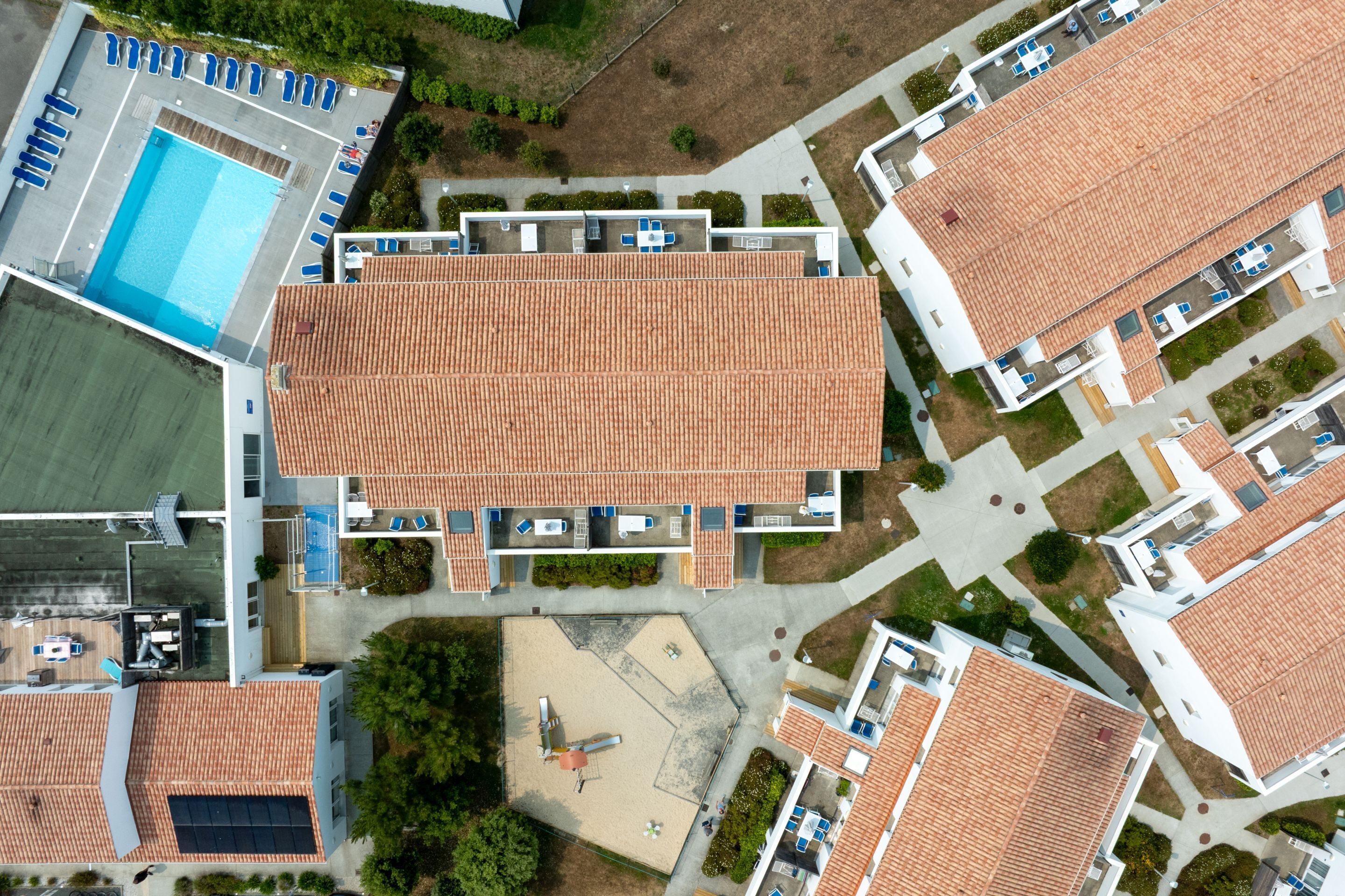 An aerial view of a residential area with multiple buildings, a swimming pool, and a tennis court.