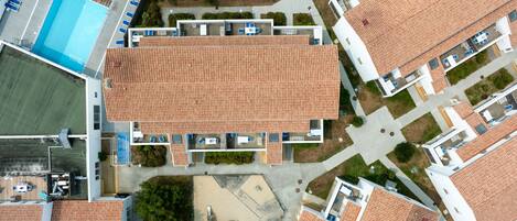 An aerial view of a residential area with multiple buildings, a swimming pool, and a tennis court.