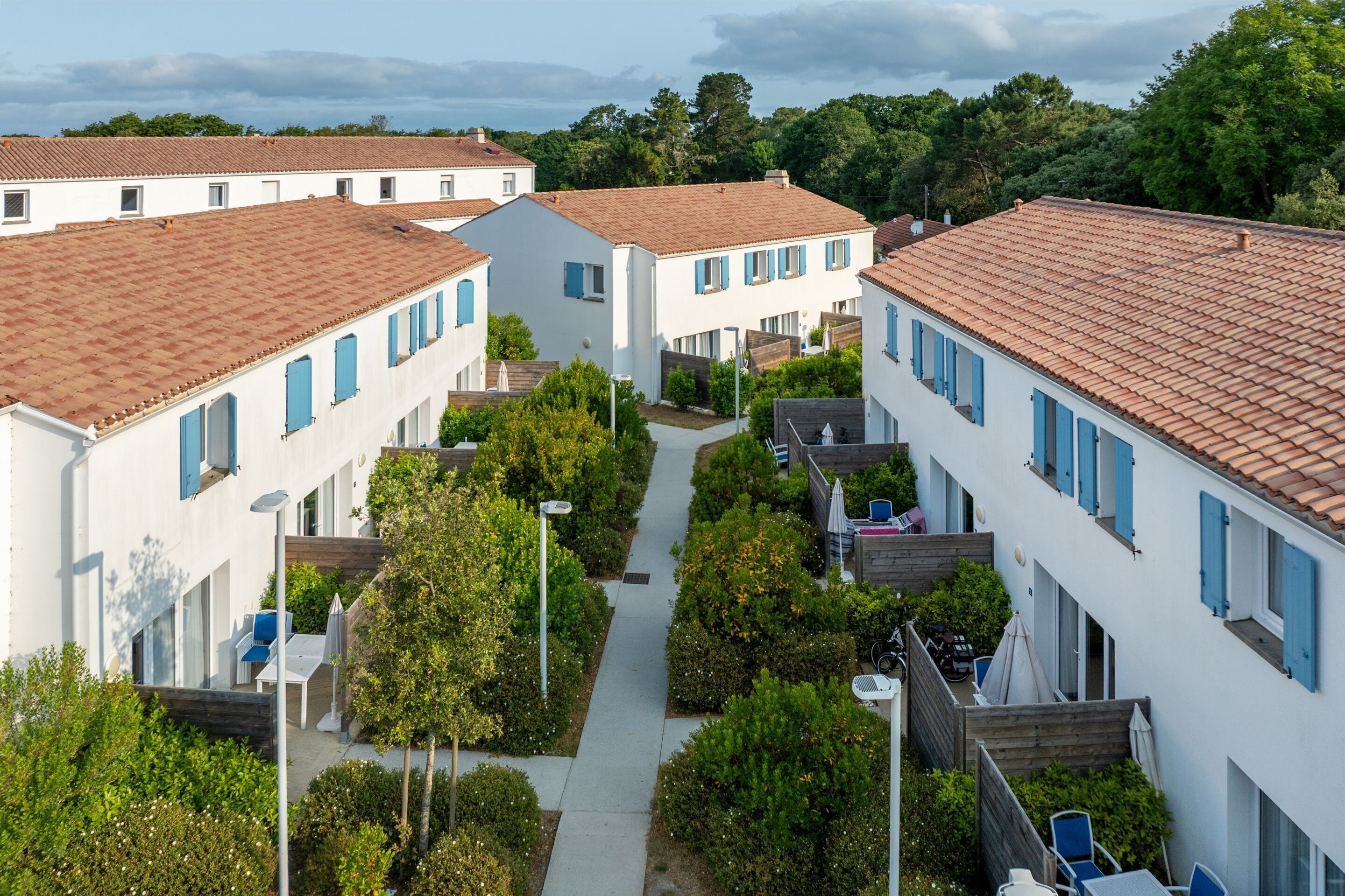 A residential area with white buildings, red-tiled roofs, and a central pathway.