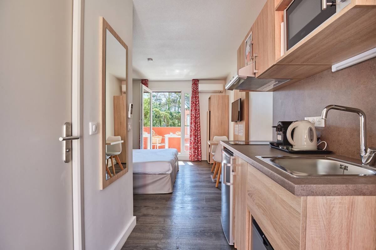 A compact kitchen with wooden cabinets, a stainless steel sink, and a microwave.