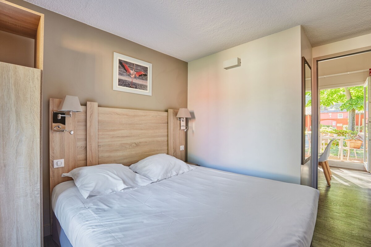 Cama bem arrumada com lençóis brancos em quarto com cabeceira e abajures de madeira.