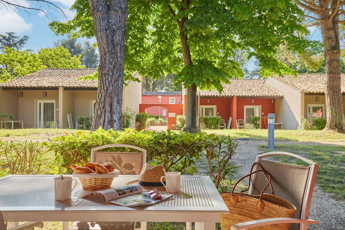 A table set outdoors with a basket of bread, a mug, and a newspaper.