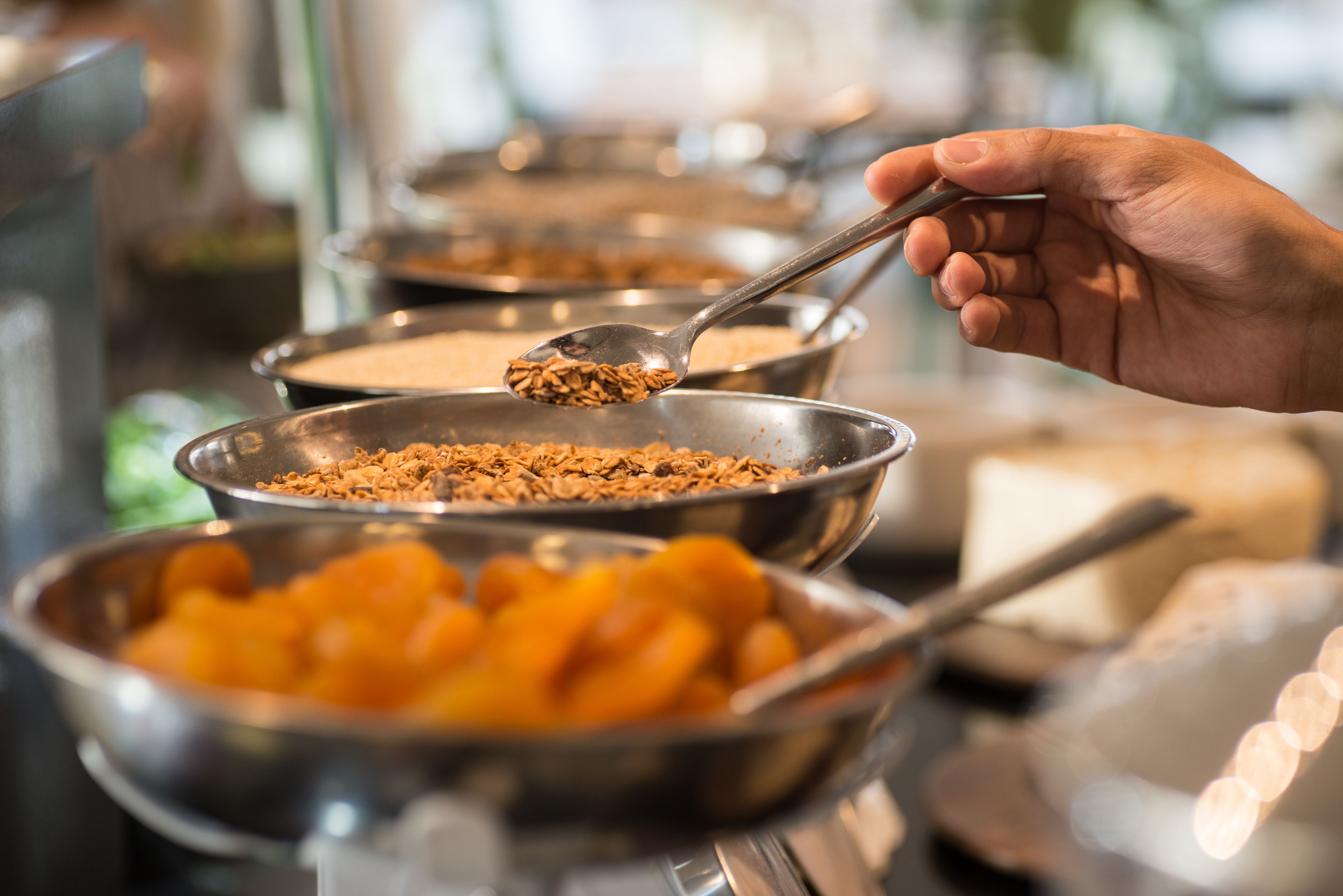 A buffet with various food items in metal bowls, including what appears to be cereal and orange slices.