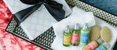 Una caja de regalo con lazo negro, rodeada de diversos productos de cuidado corporal de L'OCCITANE sobre una bandeja.