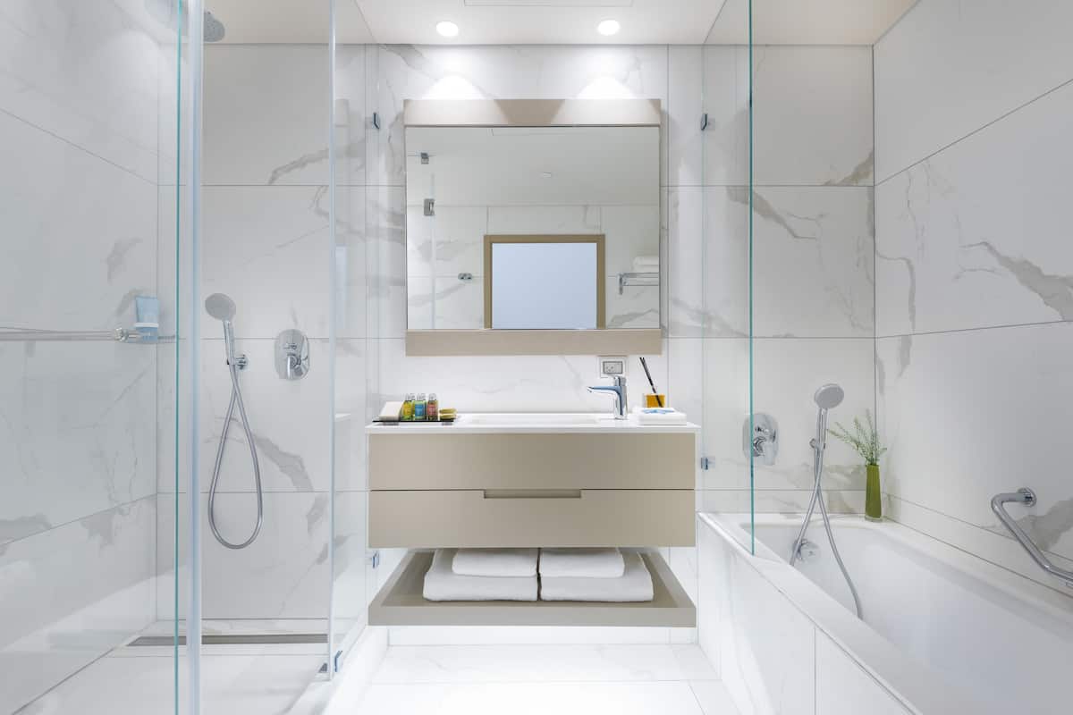 Ein modernes Badezimmer mit einer gläsernen Duschkabine, einem Waschtisch mit Spiegel und einer Badewanne.