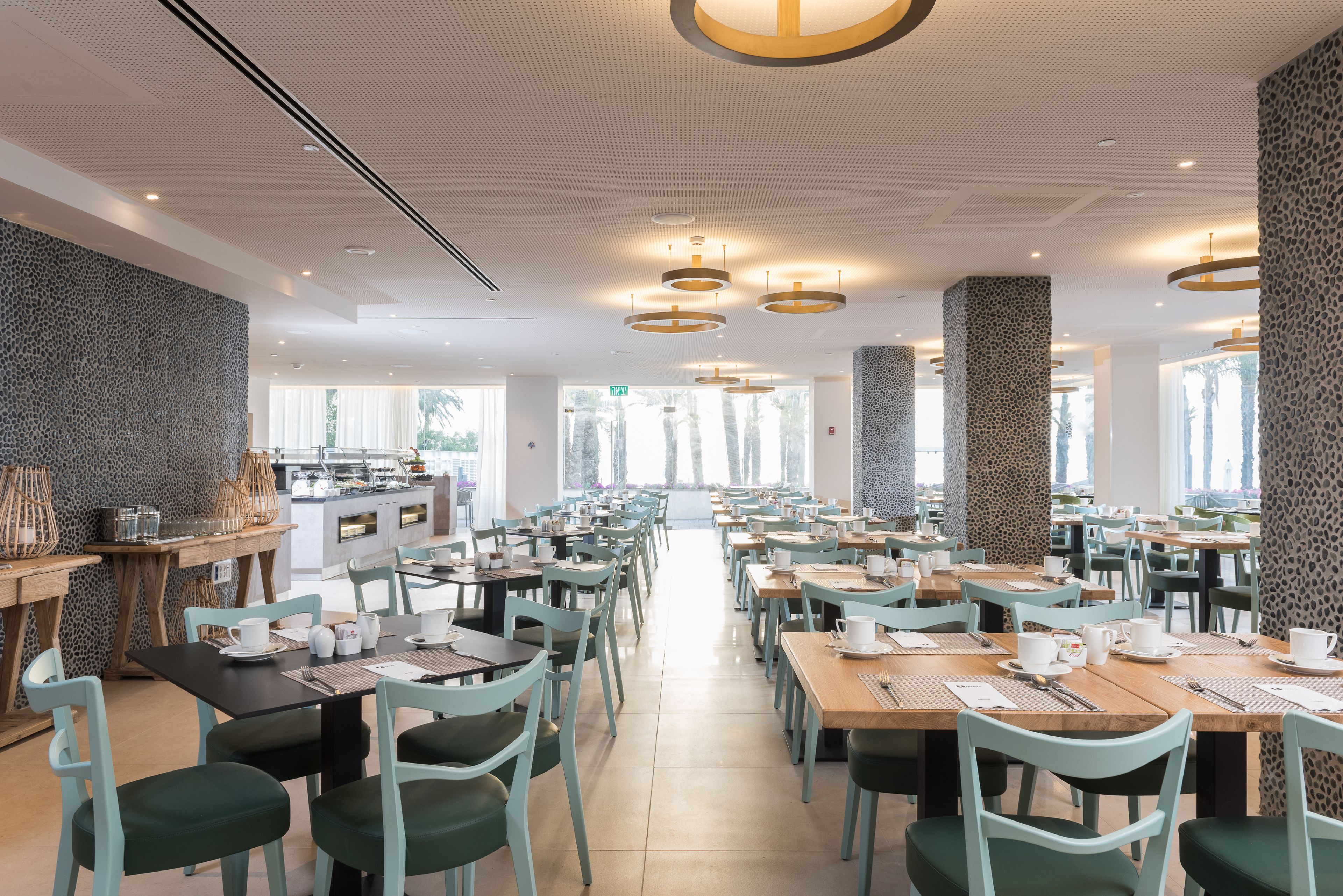 A spacious dining area with multiple tables and chairs, a central counter with a view, and a patterned wall.