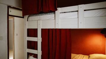 A bunk bed with red curtains and patterned pillows.