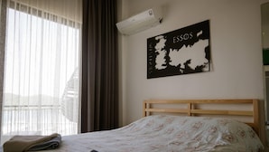 A hotel room with a bed, a window with curtains, an air conditioning unit, and a wall map. - El Camino Hostel & Pub (Fethiye)