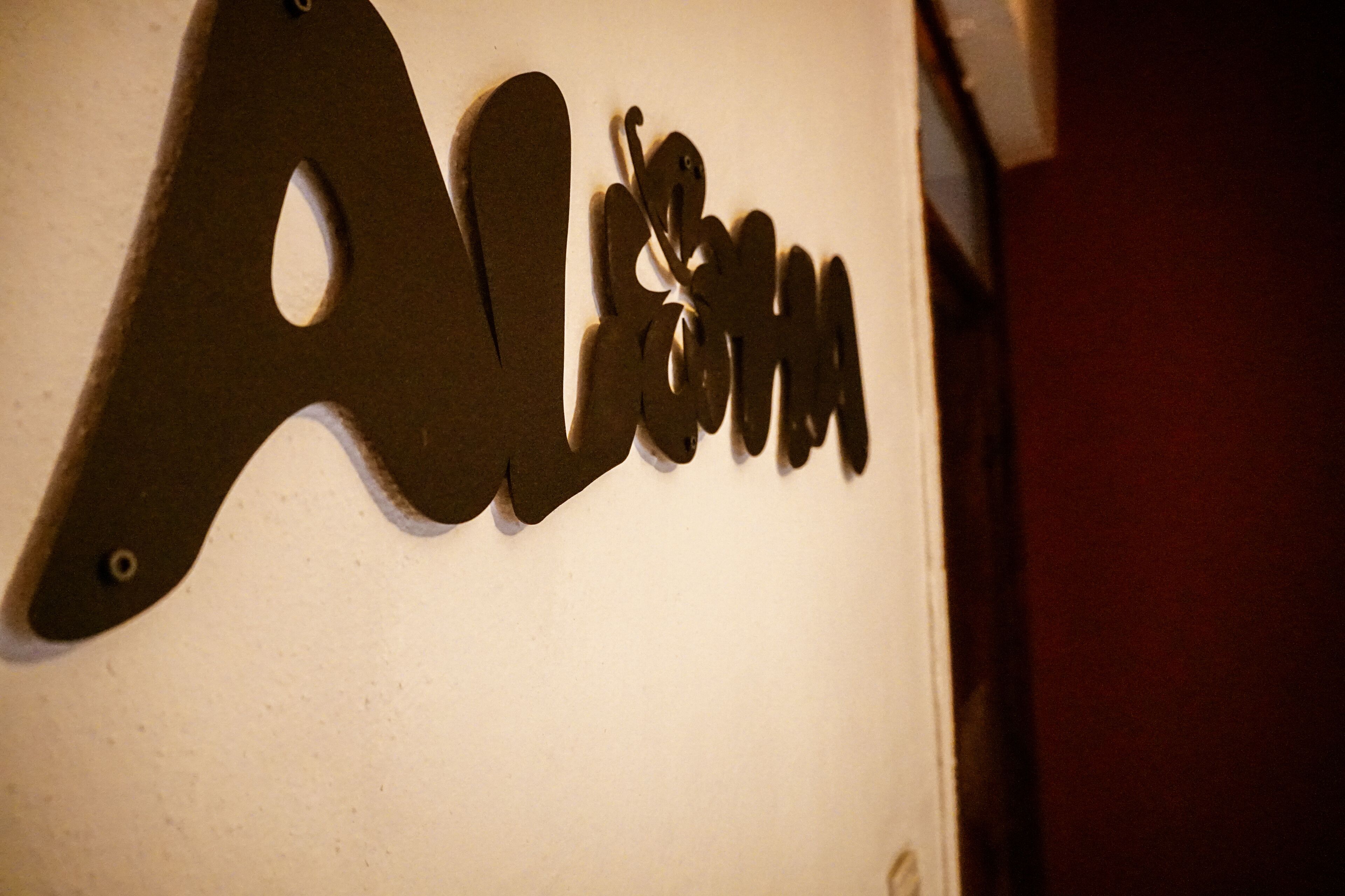 Una pared con un letrero de metal que dice 'Alumni'.