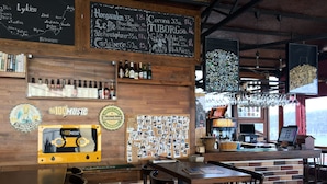 A bar area with wooden furniture, a chalkboard menu, and a wall decorated with photos. - El Camino Hostel & Pub (Fethiye)