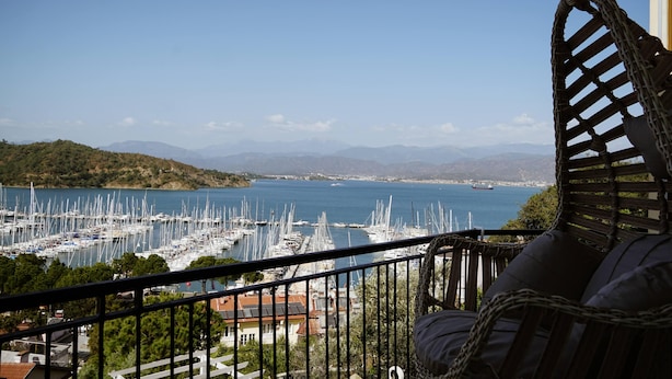 A balcony with a view of a marina and distant mountains. - El Camino Hostel & Pub (Fethiye)