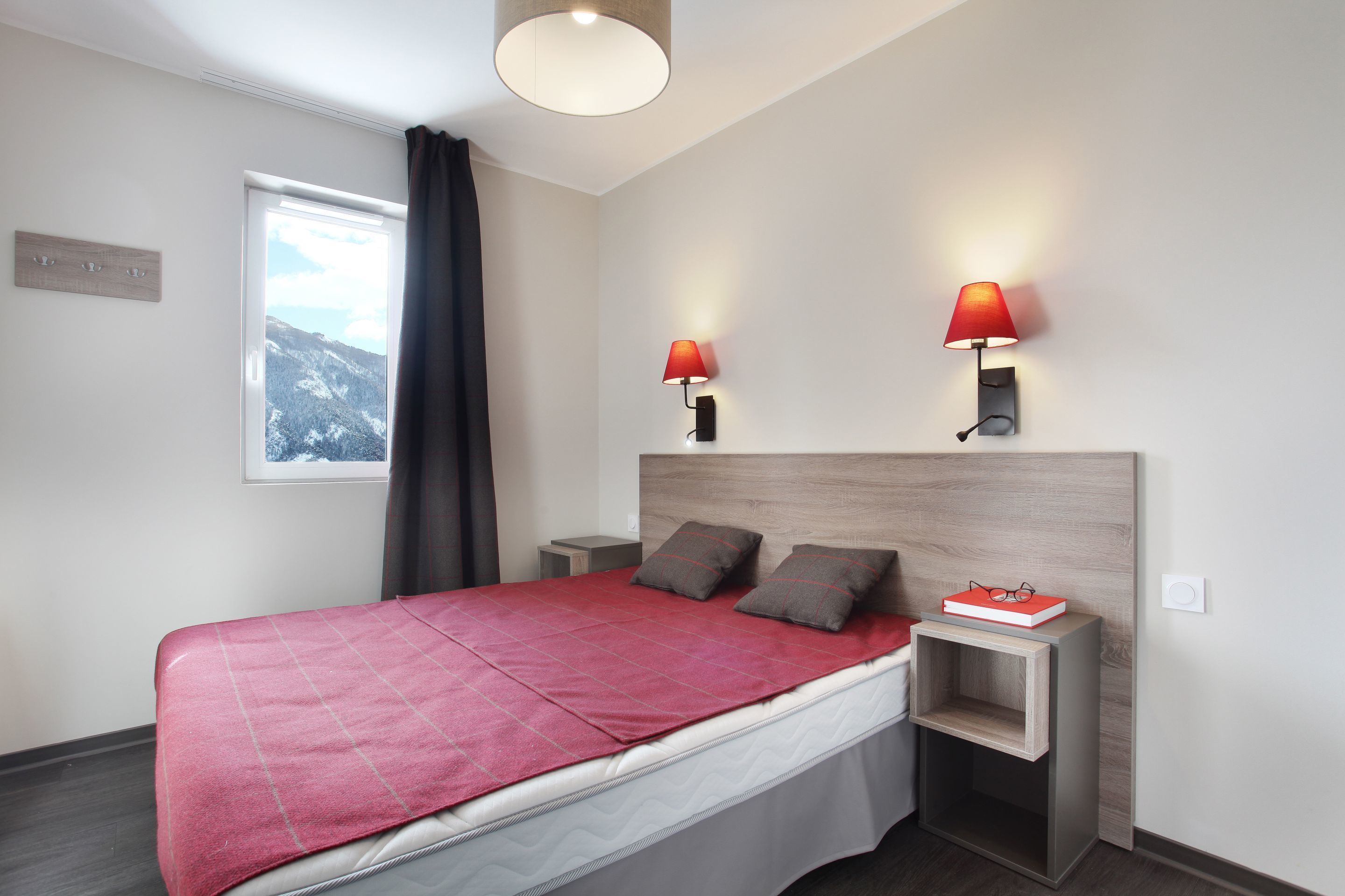 A modern bedroom with a large bed, two bedside tables, a headboard, and two wall-mounted lamps.