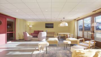Un salon moderne avec un canapé, des fauteuils, une table basse et une vue sur un paysage enneigé, visible à travers de grandes fenêtres.