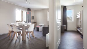 Une pièce moderne et bien éclairée, comprenant une table à manger, des chaises, un canapé et un lit.
