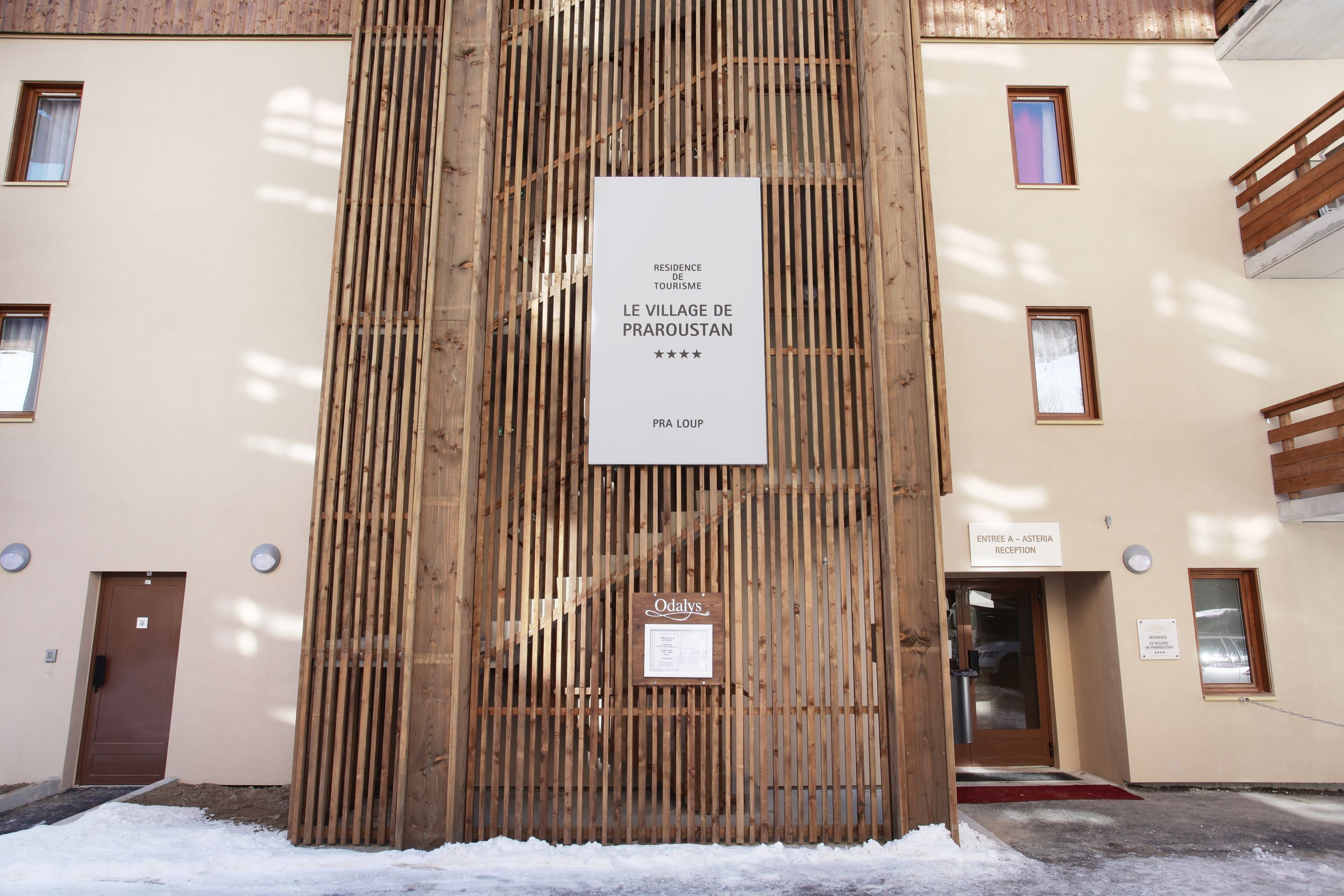 A building facade with a vertical wooden slat design, a reception sign, and a door labeled "Odaly's."