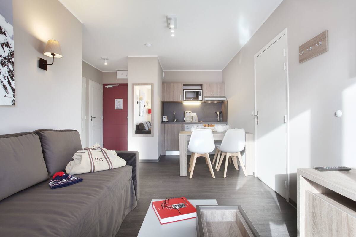A modern apartment with a living room, kitchenette, and dining area.