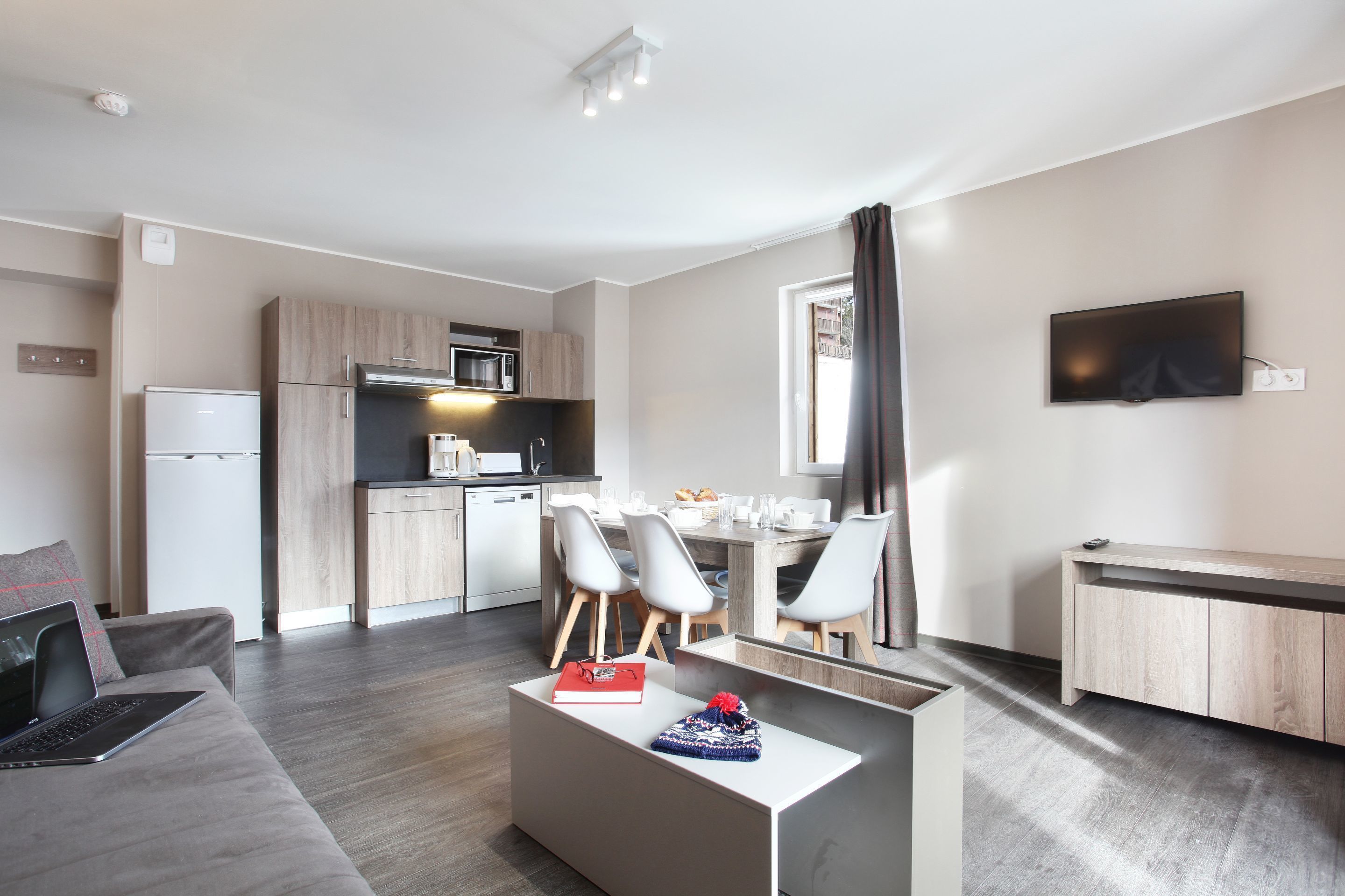 Un appartement moderne comprenant un coin cuisine, un espace repas et un salon avec un canapé et une table basse.
