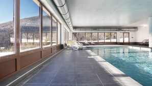 Une piscine intérieure offrant une vue dégagée sur un paysage enneigé grâce à de grandes fenêtres.