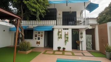 A modern house with a pool, a balcony, and a garden.