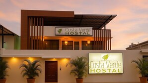 A Costa Verde HOSTAL building with a modern design, featuring a large signboard and potted plants in front. - Hostal Costa Verde (Manta)