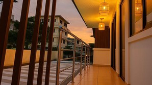 A corridor with a modern design, featuring a railing, a ceiling with a radial light fixture, and a view of buildings in the background. - Hostal Costa Verde (Manta)