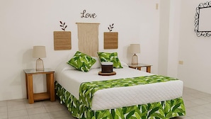 A bedroom with a bed, two nightstands, a wall-mounted air conditioner, and decorative wall hangings. - Hostal Costa Verde (Manta)