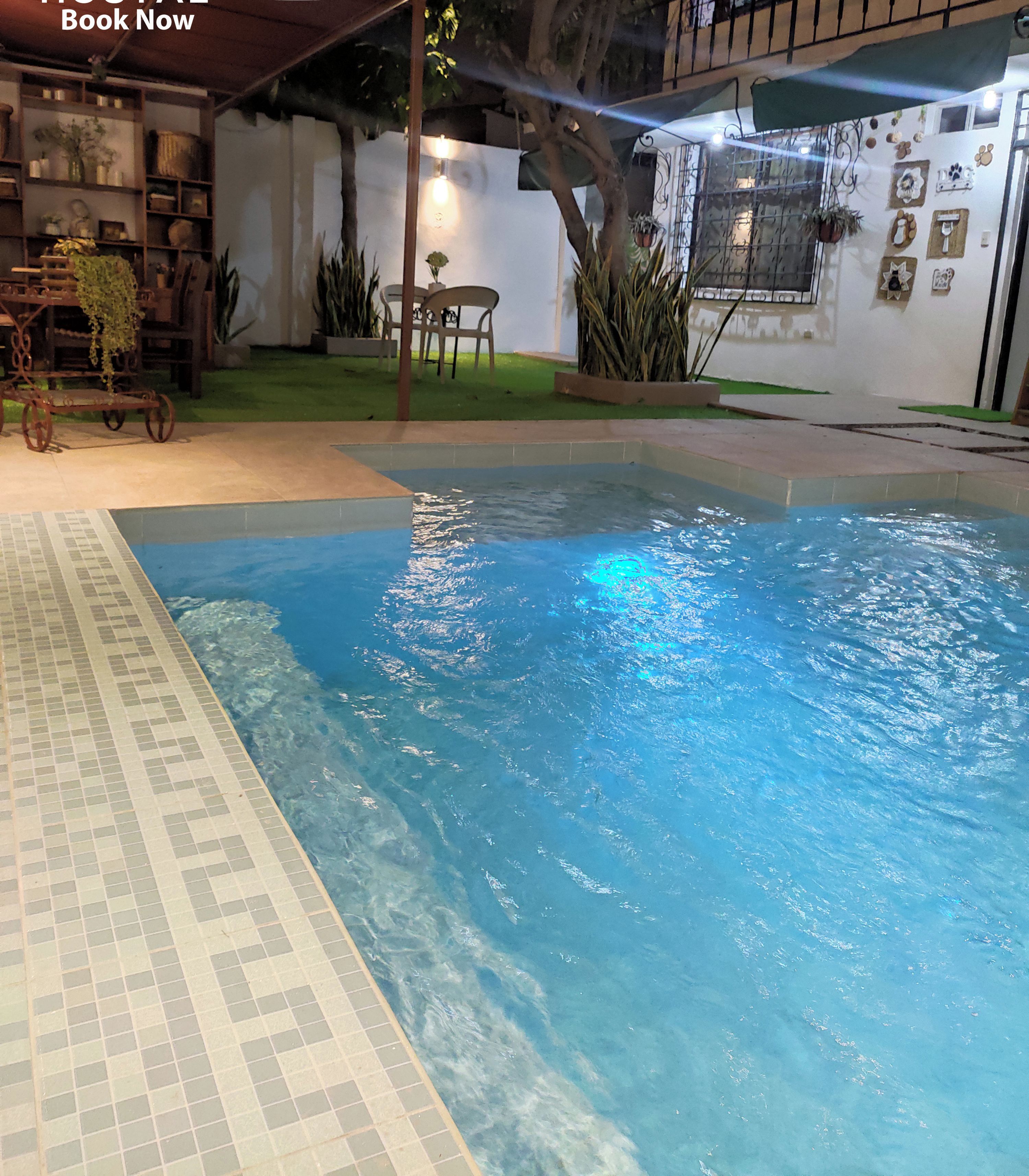 A pool area with a tiled edge, a small table with chairs, and a potted plant.