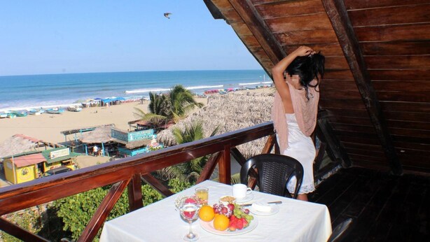 Varanda com mesa posta para o café da manhã, com vista para a praia.