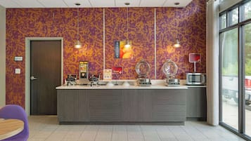 A modern kitchen with a marble countertop, a microwave, and a coffee machine.