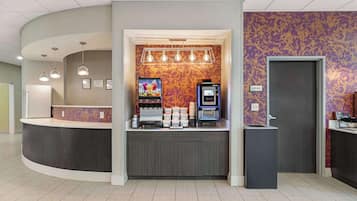 A reception area with a curved counter, a coffee machine, and a small refrigerator.