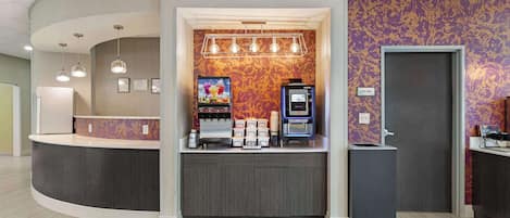 A reception area with a curved counter, a coffee machine, and a small refrigerator.