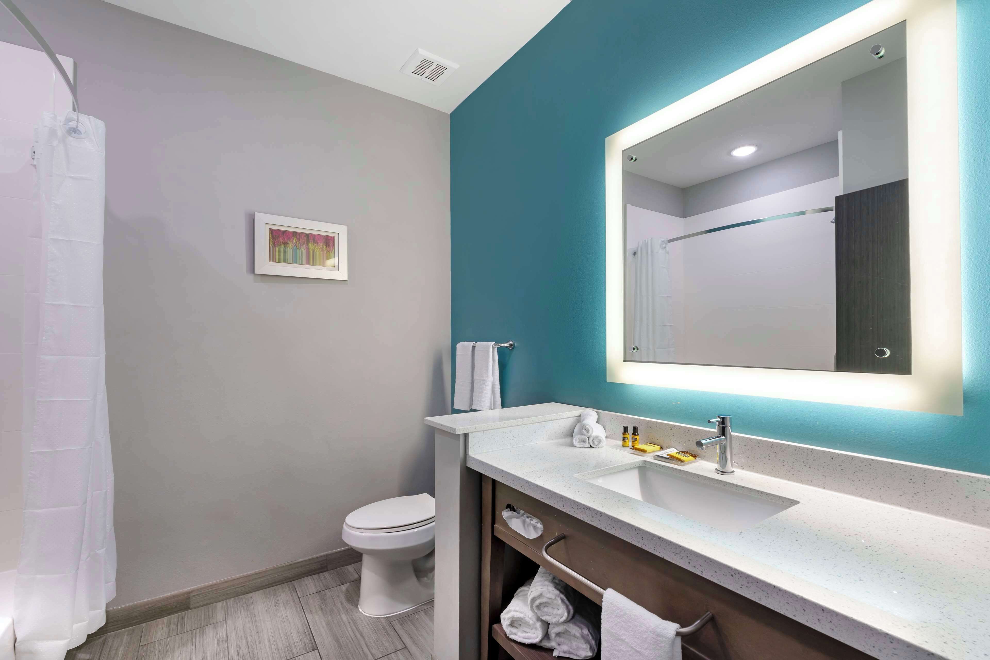 Un bagno moderno con il water bianco, un lavandino con uno specchio e una tenda per la doccia.