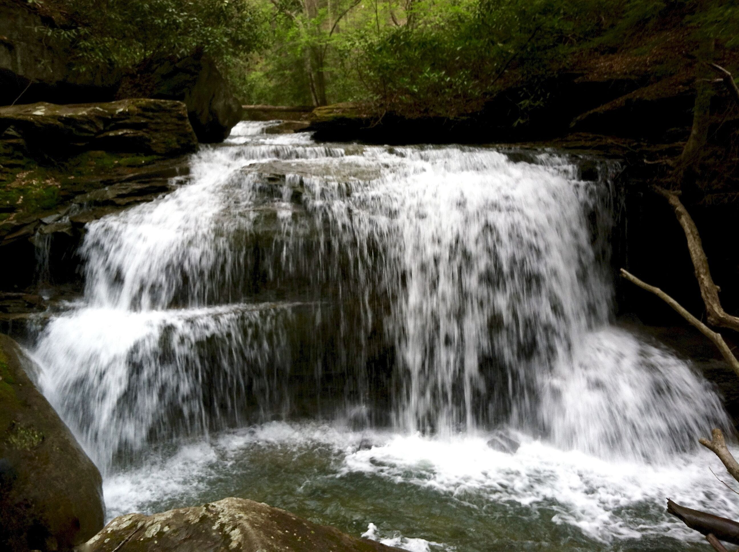 A waterfall cascading over rocks in a forested area.