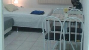 A small, single-room accommodation with a bed, a desk, and a chair. - Studio One (Rio de Janeiro)