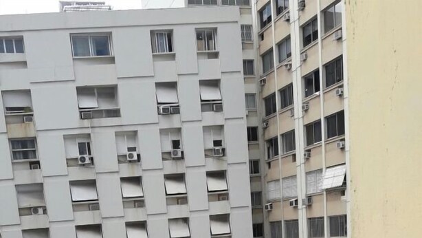 A high-rise building with a grid-like facade, multiple balconies, and air conditioning units. - Studio One (Rio de Janeiro)