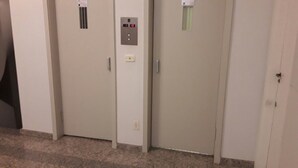 A hallway with three beige doors, each with a small vent and a control panel with a digital display. - Studio One (Rio de Janeiro)