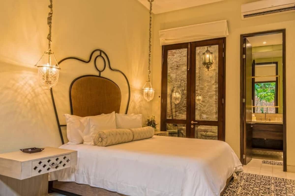 Un dormitorio con cama, mesita de noche y dos lámparas fijadas a la pared.