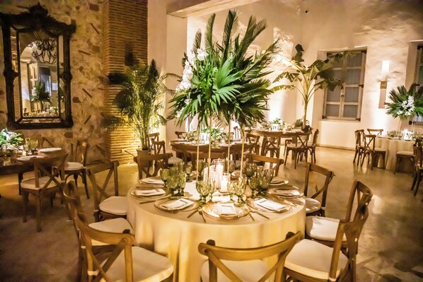 Comedor con mesas redondas dispuestas para varios comensales, rodeado de sillas.