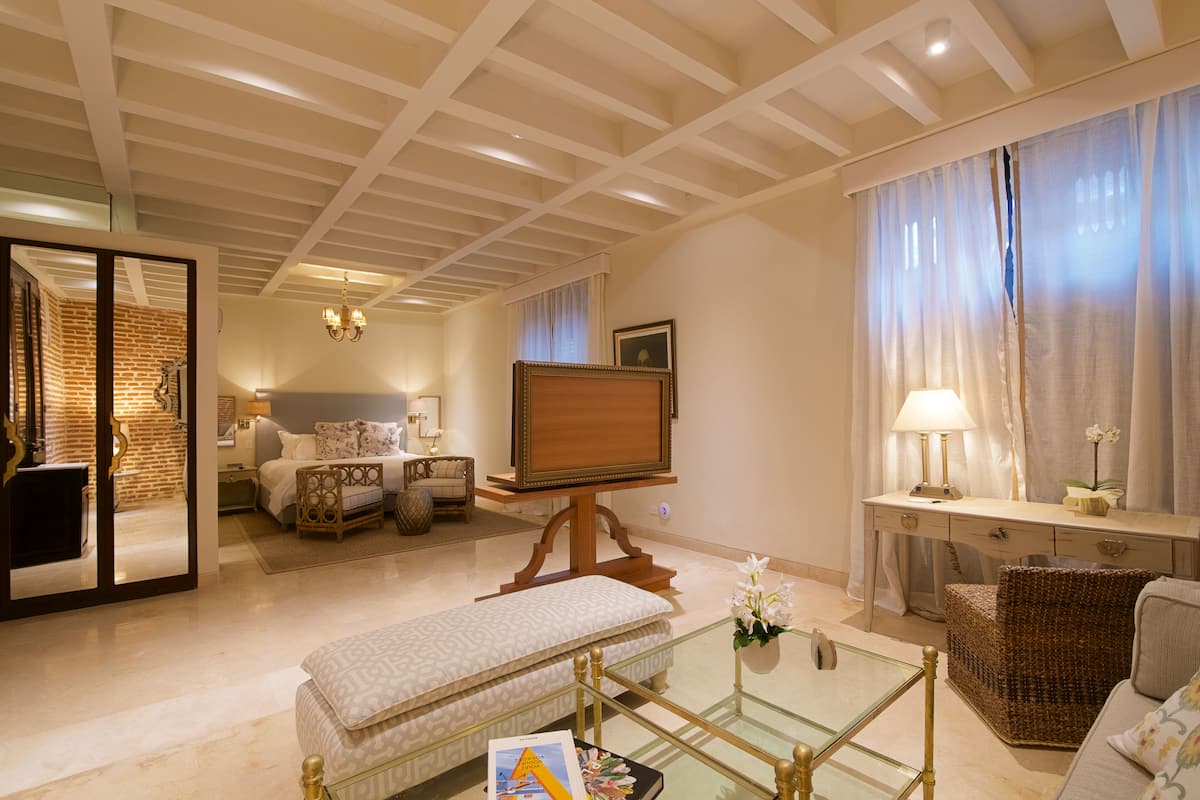 Un salón luminoso con televisor, sofá y mesa de centro de vidrio.