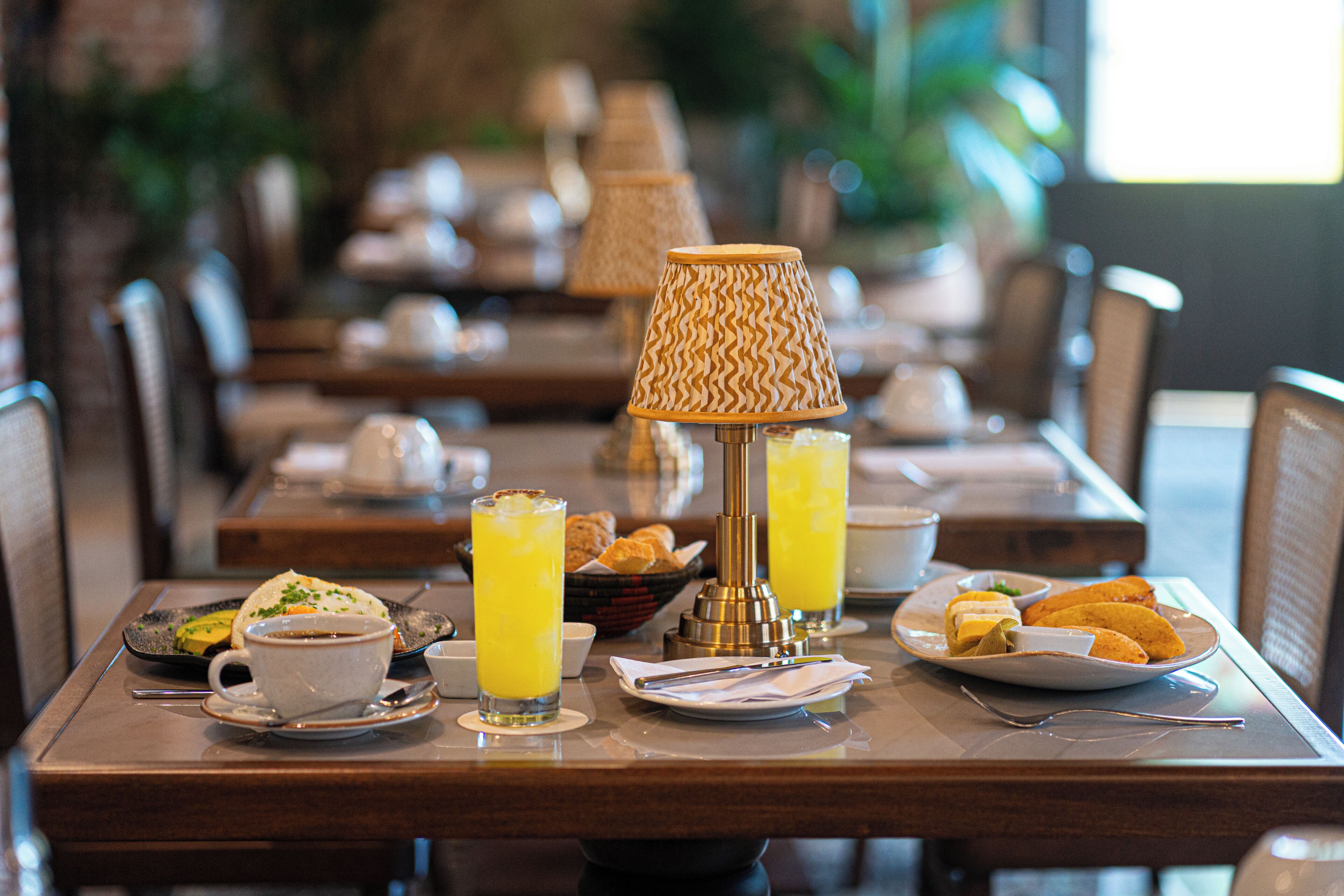 A dining table with breakfast items, including a cup, a plate with pastries, and a bottle of orange juice.