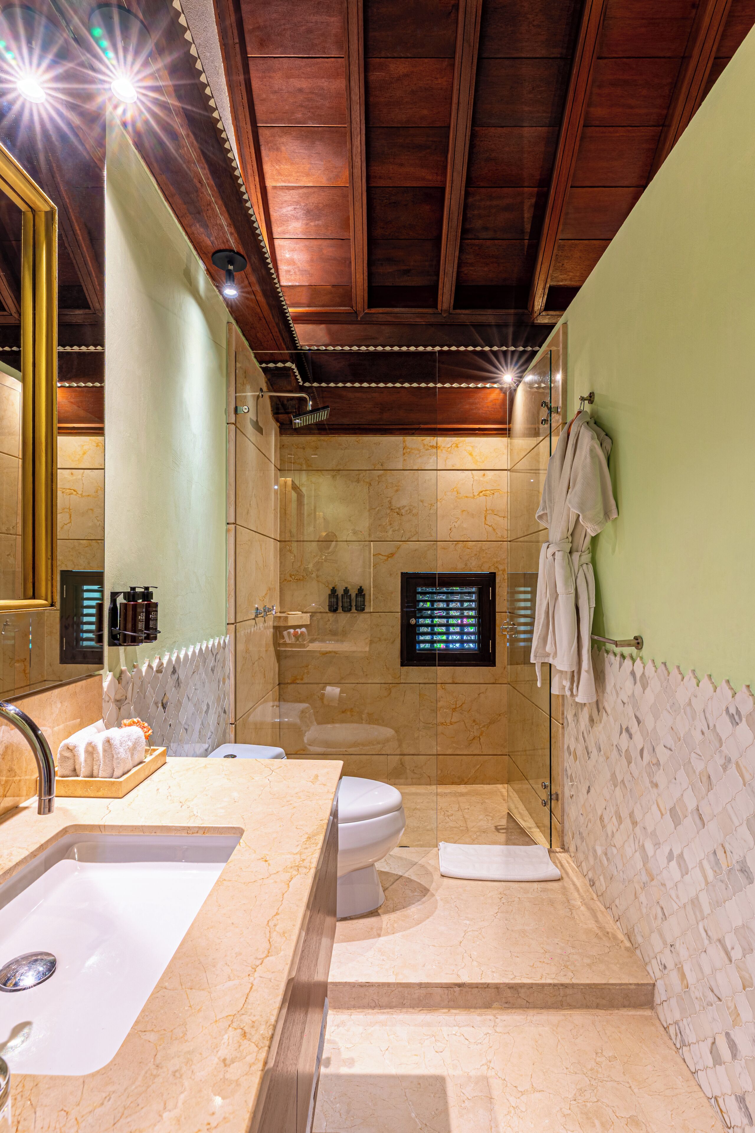 A bathroom with a marble sink, a toilet, a shower, and a glass-enclosed shower area.