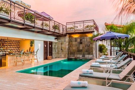 Una piscina techada, una piscina al aire libre, sombrillas