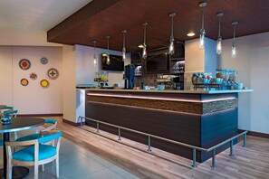A modern bar area with a counter, seating, and decorative plates on the wall. - Fairfield by Marriott San Salvador (Antiguo Cuscatlán)