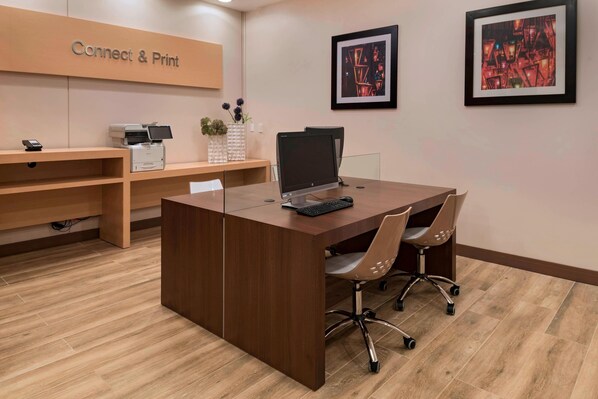 Un mostrador de recepción con un cartel que dice "Connect & Print", una computadora y una silla.