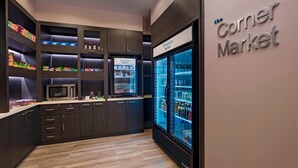 A modern kitchen with dark wood cabinets, a microwave, and a refrigerator. - Fairfield by Marriott San Salvador (Antiguo Cuscatlán)