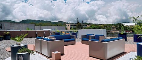 Un área de estar al aire libre con sofás y jardineras, rodeada por una terraza de madera y grava.