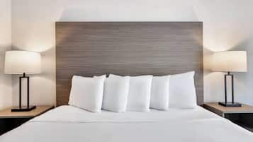 A hotel room with a large bed, two bedside tables with lamps, and a wooden headboard.