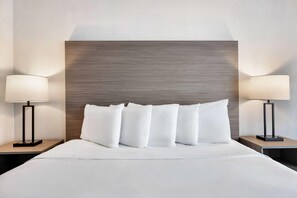 A hotel room with a large bed, two bedside tables with lamps, and a wooden headboard. - AmericInn by Wyndham Baxter Brainerd (Baxter)